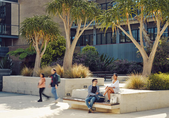 A group of students sitting and walking outdoors at the Geelong Waurn Ponds Campus.