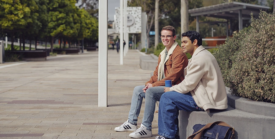 Two Deakin students sit on a bench at the Melbourne Burwood Campus.