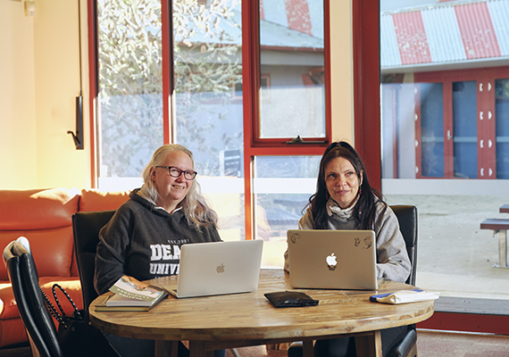Two students sit at a table with laptops at the NIKERI Institute, Deakin University. 