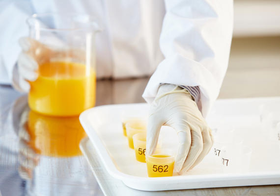 Deakin nutrition and dietetics with gloves sets out samples of orange juice.