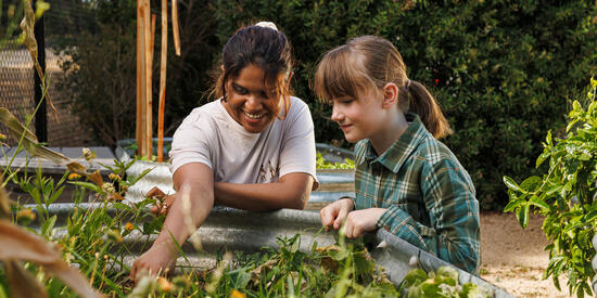 Two young girls inspect a raised garden bed.