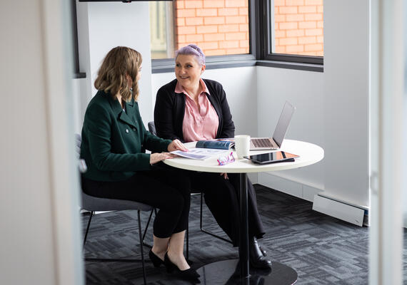 Two female human resource psychology students in and interview at a table
