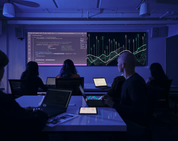 Students in a dark classroom looking at a projector