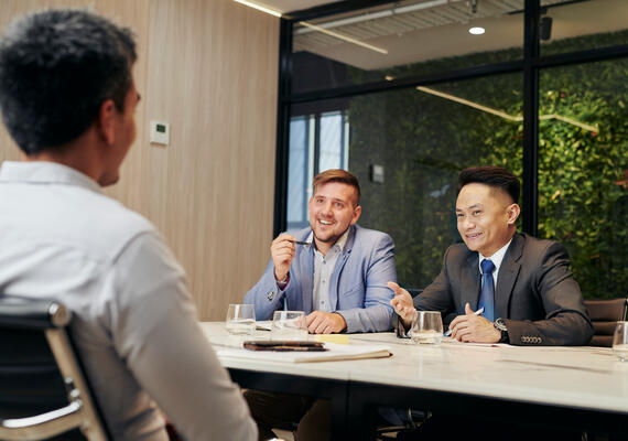 Three business students siting at a table, in conversation.