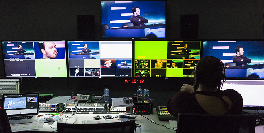 Deakin student sitting in front of a wall of screens in the media studios.