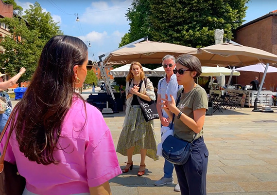 MBA students on a European study tour listen to a tour guide in a city square..