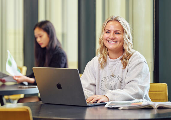 A student at a computer, smiling.
