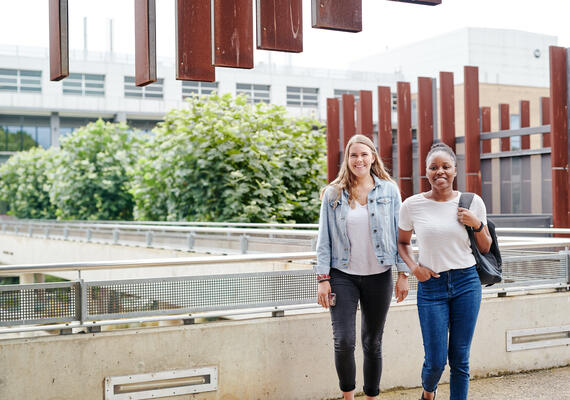 Two students smiling, standing outside near the bridge at the Deakin Waurn Ponds Campus.