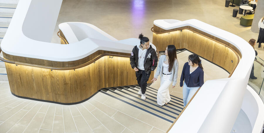 Three Deakin students walk up the stairs of the Burwood law building