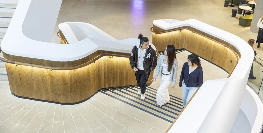 Three Deakin students walk up the stairs of the Burwood law building