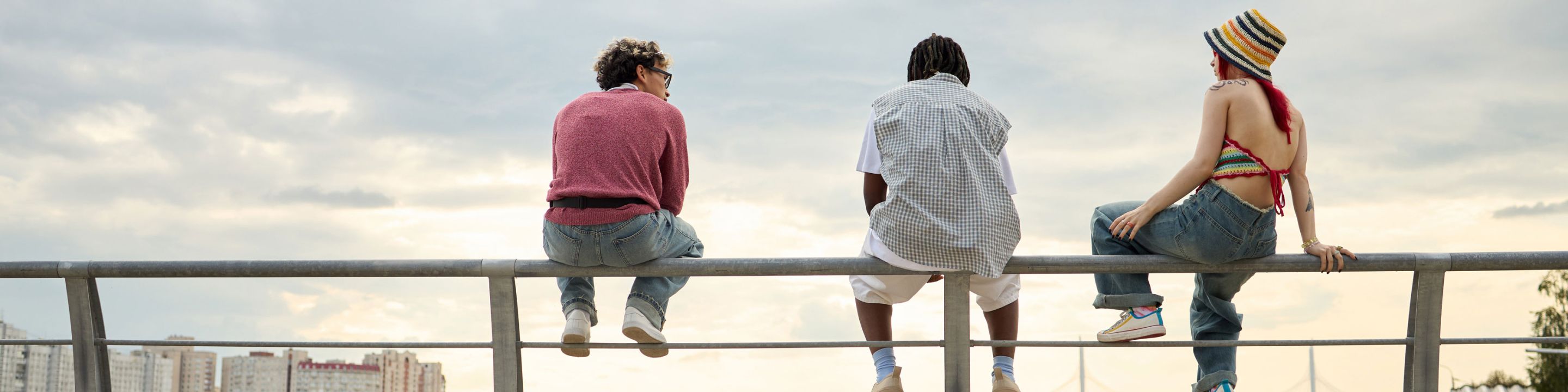 Three students sitting on railing outside talking