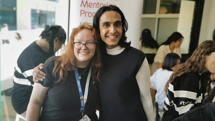Gab with his arm around a friend. Both of them are smiling.
