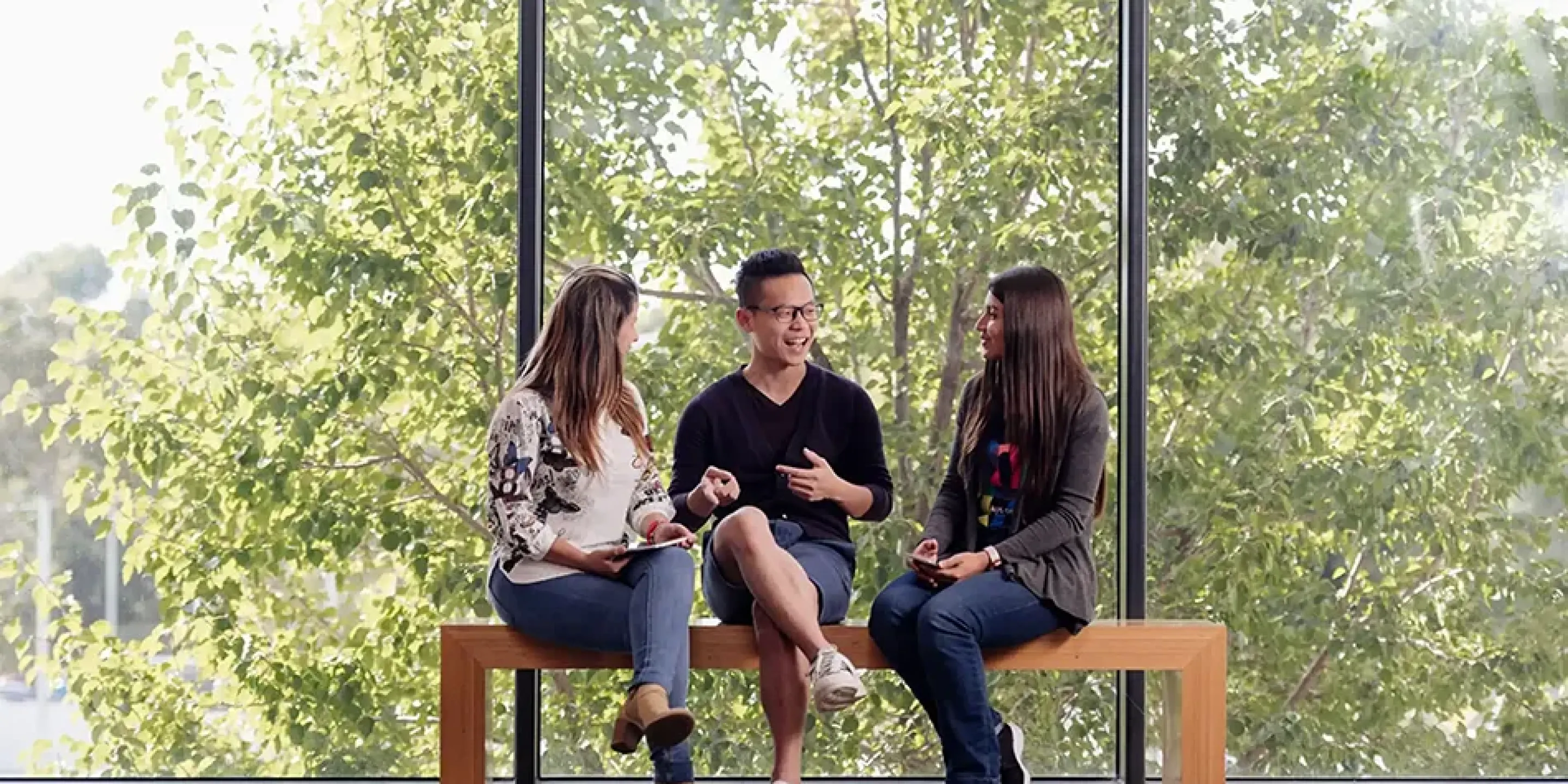 Three international students sitting outside chatting.
