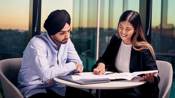 Two Deakin graduate diploma of financial planning students sitting at a table and talking.