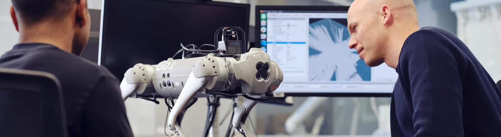 Two Deakin master of applied artificial intelligence professional students work on a robot in a lab.
