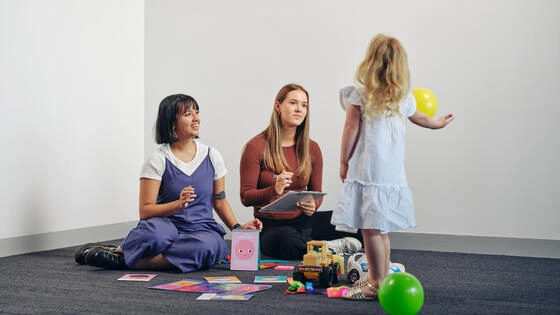 Two Deakin master of child play therapy students interact with a small child.