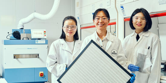Deakin researchers standing in a lab holding a filter.