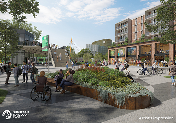 An artist's impression of what the suburban rail station will look like – lots of people sitting and standing, plus a station sign.