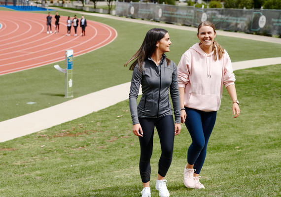 Two students walking on a grass oval