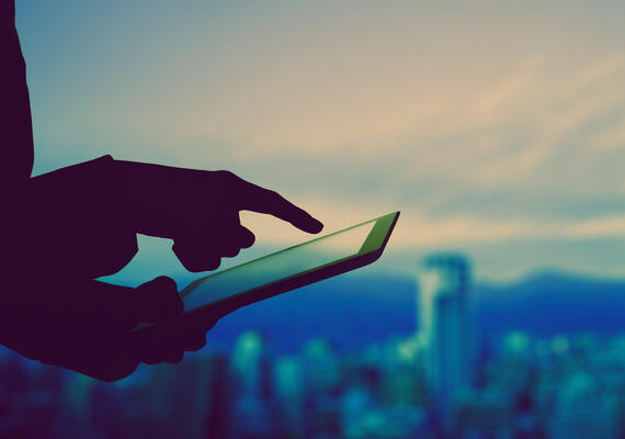 A person using a tablet with city skyline in background.