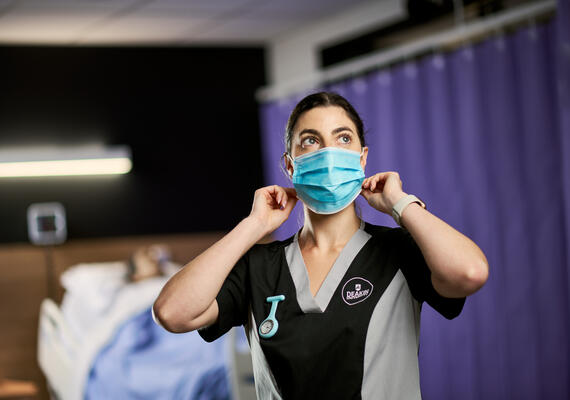 Nursing student putting mask on in clinical setting
