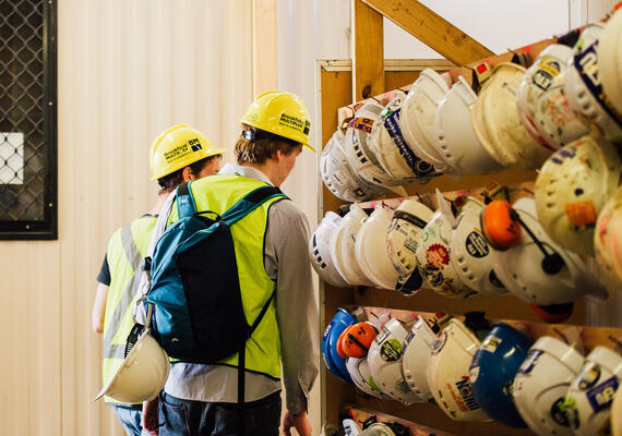 two construction management students take their safety helmets off the rack