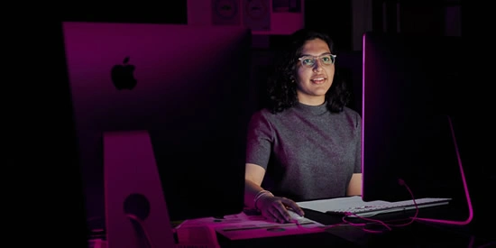 Deakin communication student using a computer in a production room on campus.