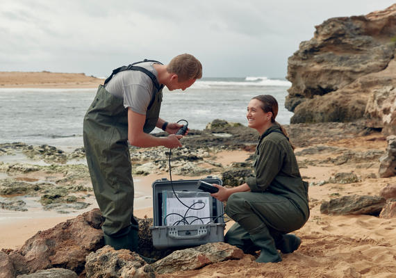 Two students collecting samples by the ocean