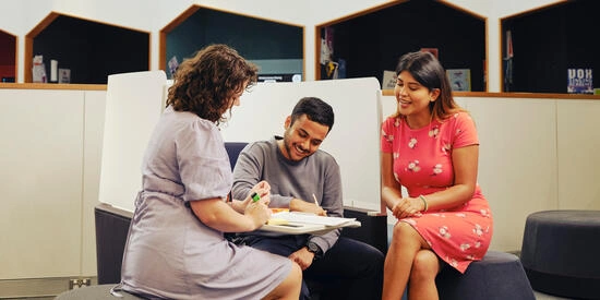 Staff interacting and assisting two students on the Burwood campus.