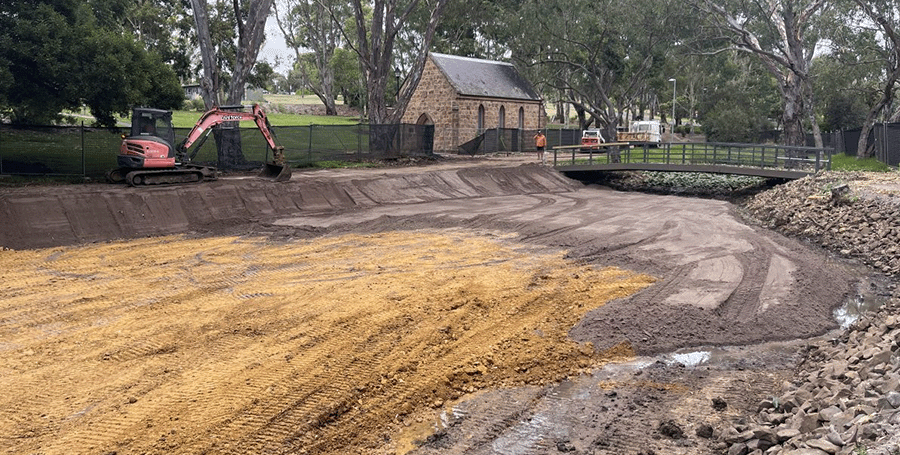Bulldozer next to empty lake and heritage building