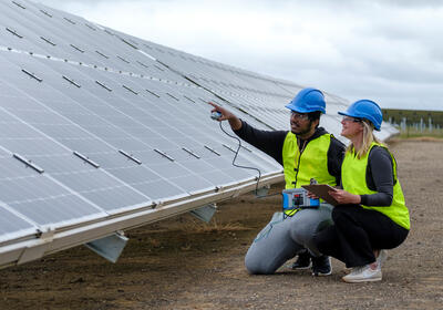 two people inspecting solar panels at a solar farm.