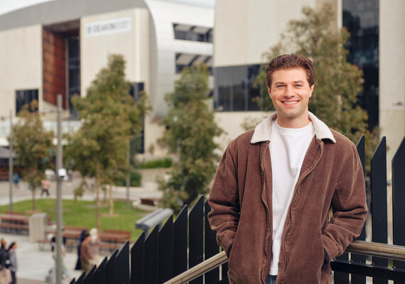 Deakin student Dante Selek standing and smiling on campus.