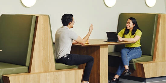 Two Deakin students sit across from each other in a booth in Building LC on the Melbourne Burwood Campus.
