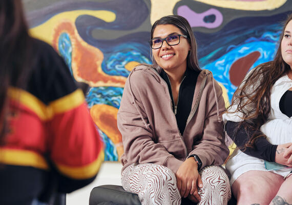 Students sitting front of a colourful painting.