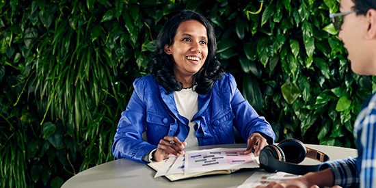 Deakin student sitting on campus talking to an advisor at a table.