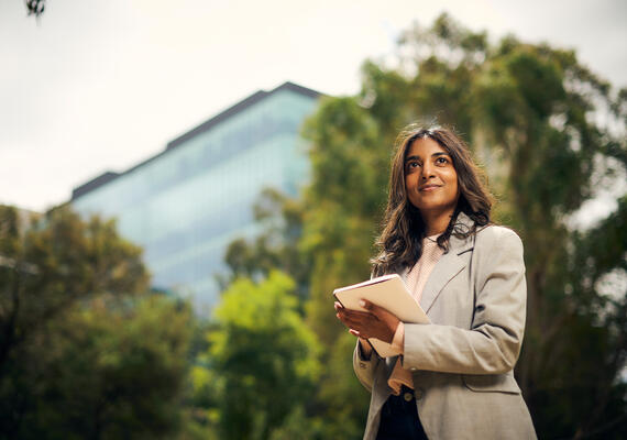 A student in a bushland setting with an office tower visible in the background