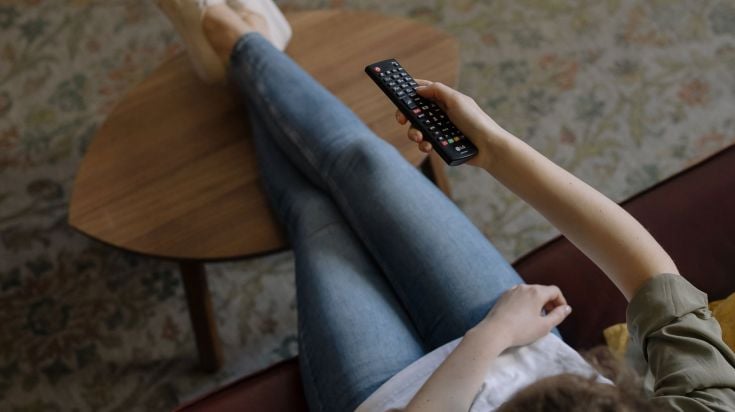 A girl on the couch with a TV remote