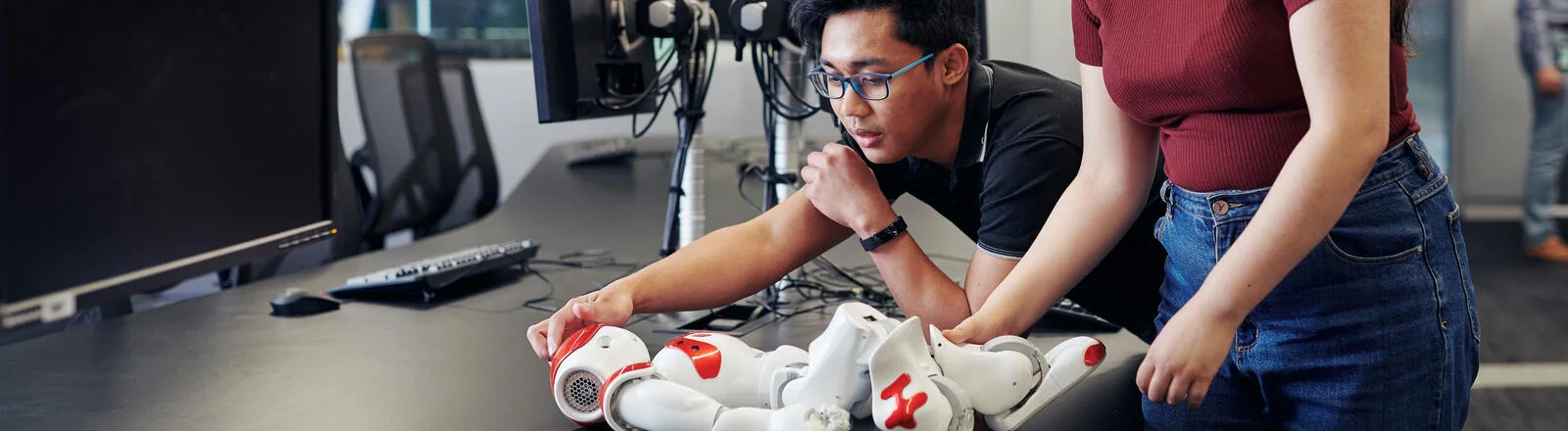 Two Deakin master of applied artificial intelligence students work together on a robot in a campus lab.
