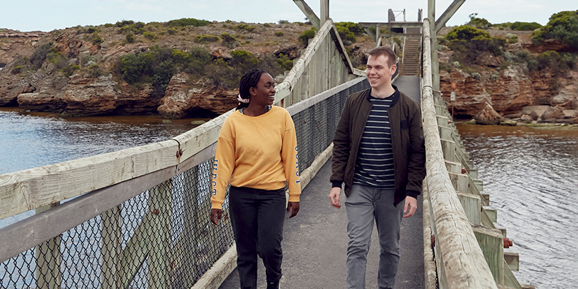 Two students walking across a bridge