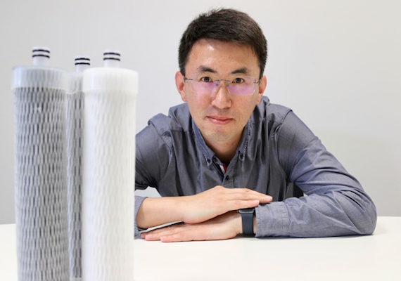 Quanxiang (Sulley) Li smiling next to water filter devies.