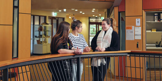 Three Deakin students chat while standing in hallway at the NIKERI Institute.