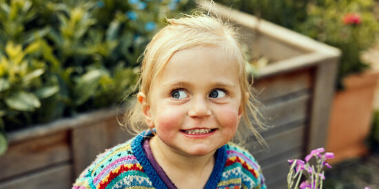 A child smiles in the garden.