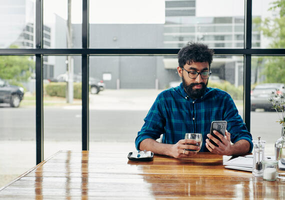 A person sits in a cafe and uses a mobile phone.
