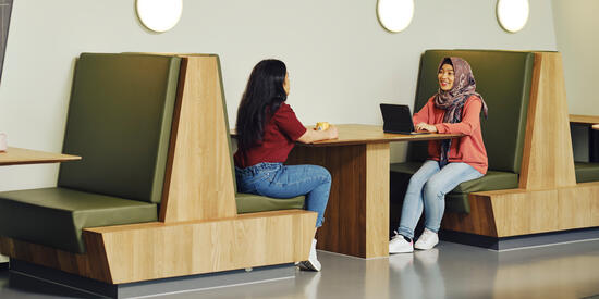 Two students sit across from each other in a booth in Building LC on the Melbourne Burwood Campus.