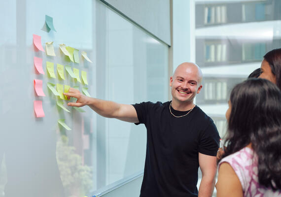 group of advertising psychology students brainstorming for an assignment on a whiteboard in a classroom
