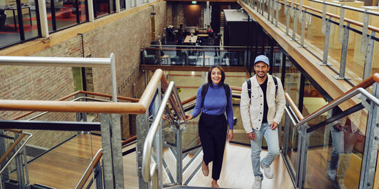 Two engineering students smiling and walking up stairs