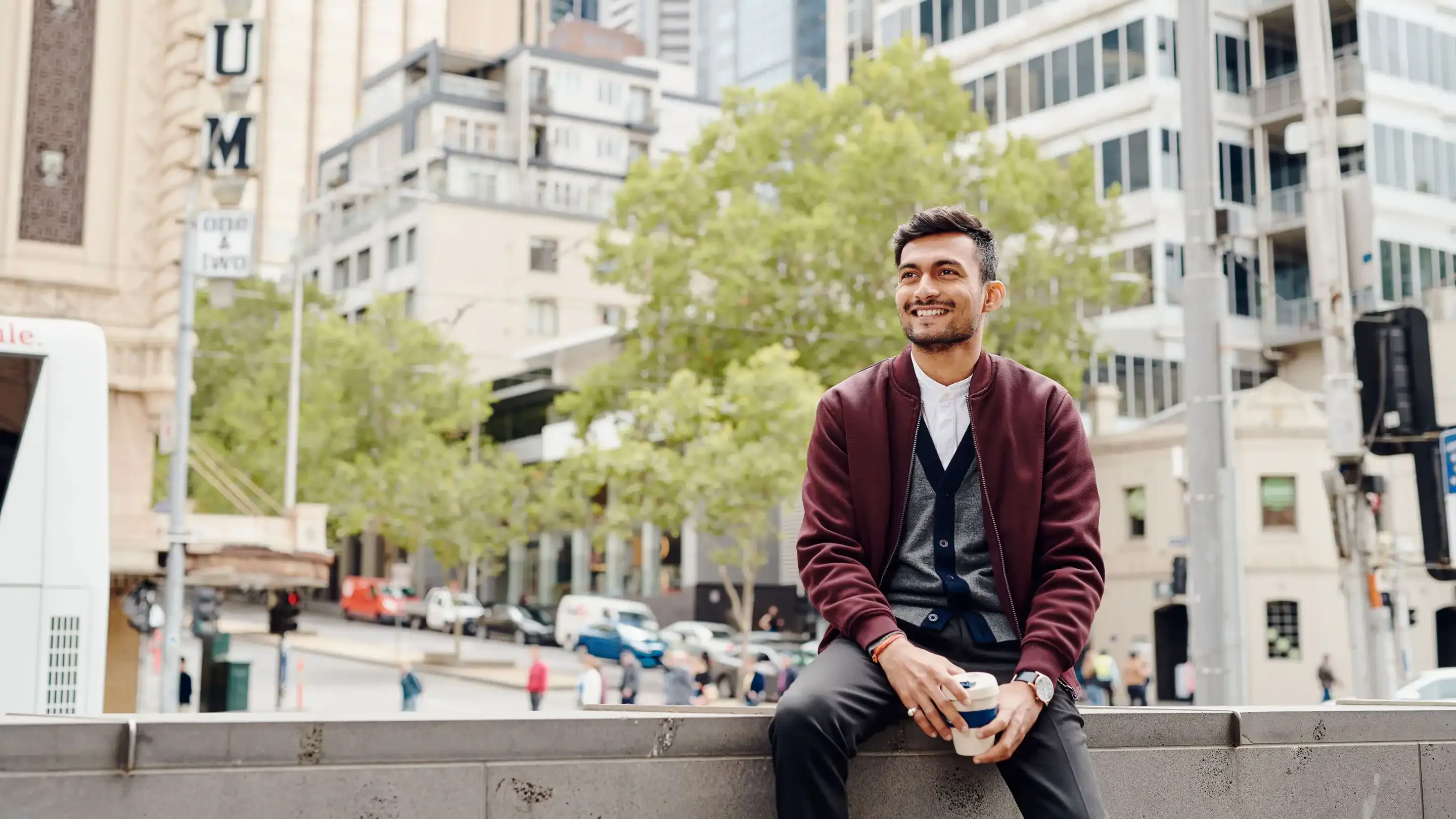 Student sitting in the CBD with a coffee