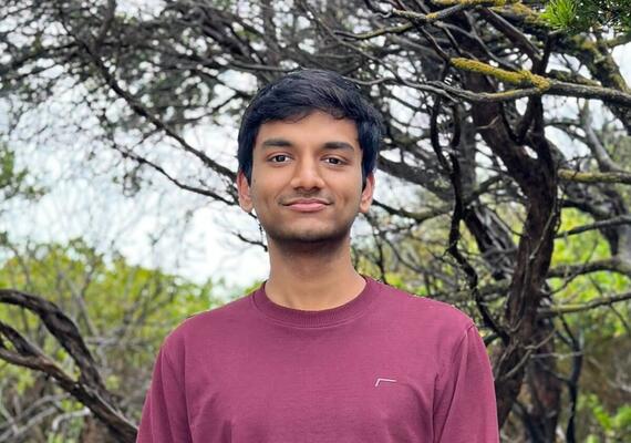 A head and shoulders photo of Deakin student Nishanth standing in front of a tree.