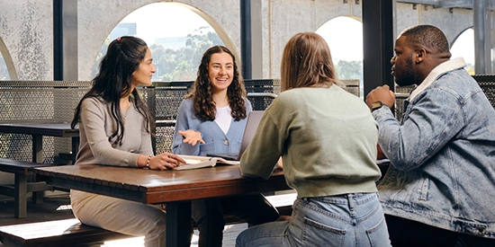 Deakin students sitting around a table talking at Student Central.