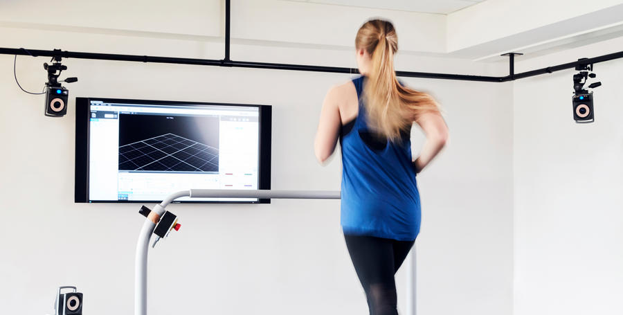 Deakin student running on a treadmill in a campus sport facility with a screen in front of them.